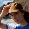 Woman wearing a brown cap with a mountainous landscape in the background
