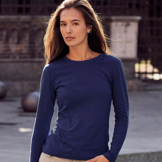 Woman wearing a blue long-sleeve top and beige pants standing on a stone path.