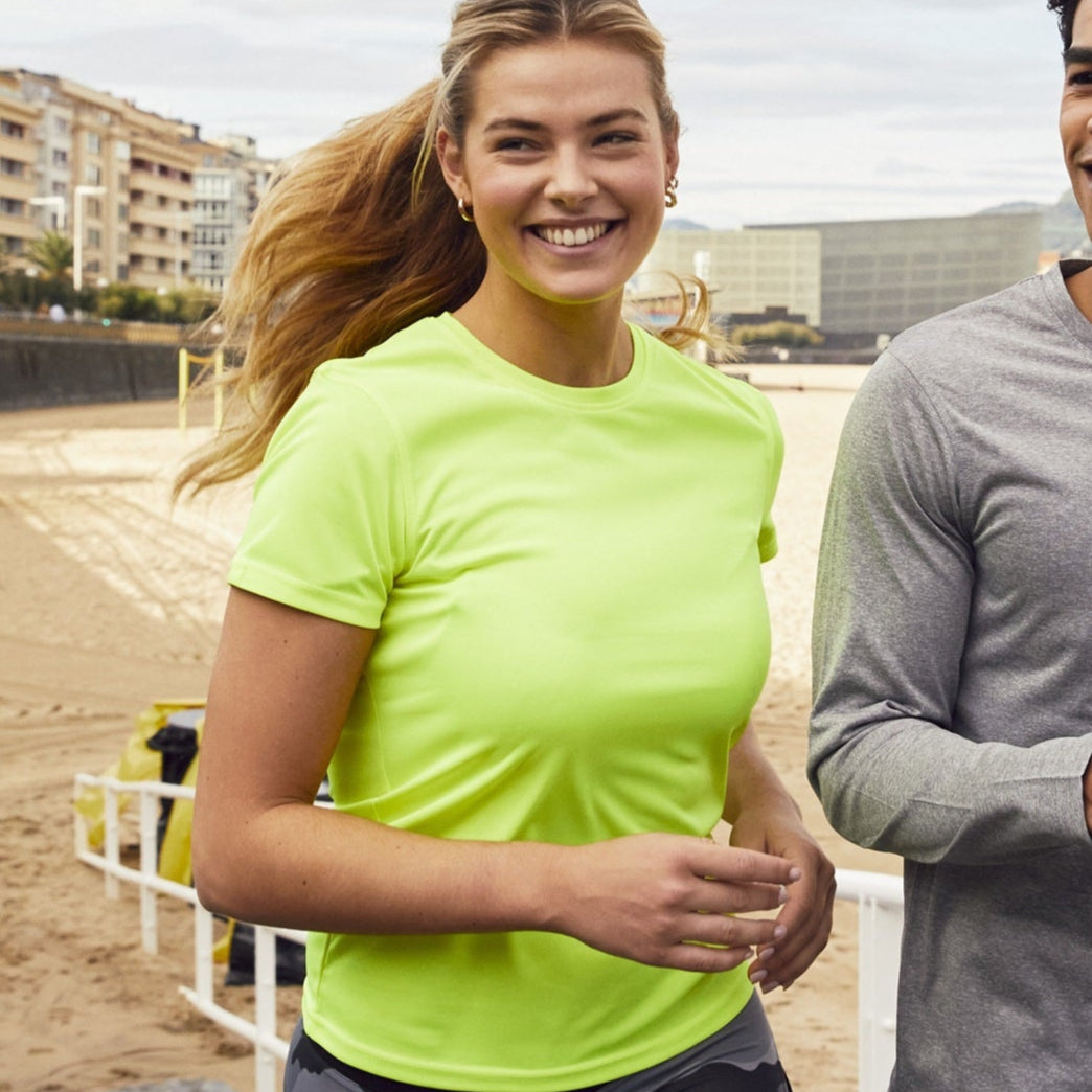 Two people walking on a path by a beach with buildings in the background