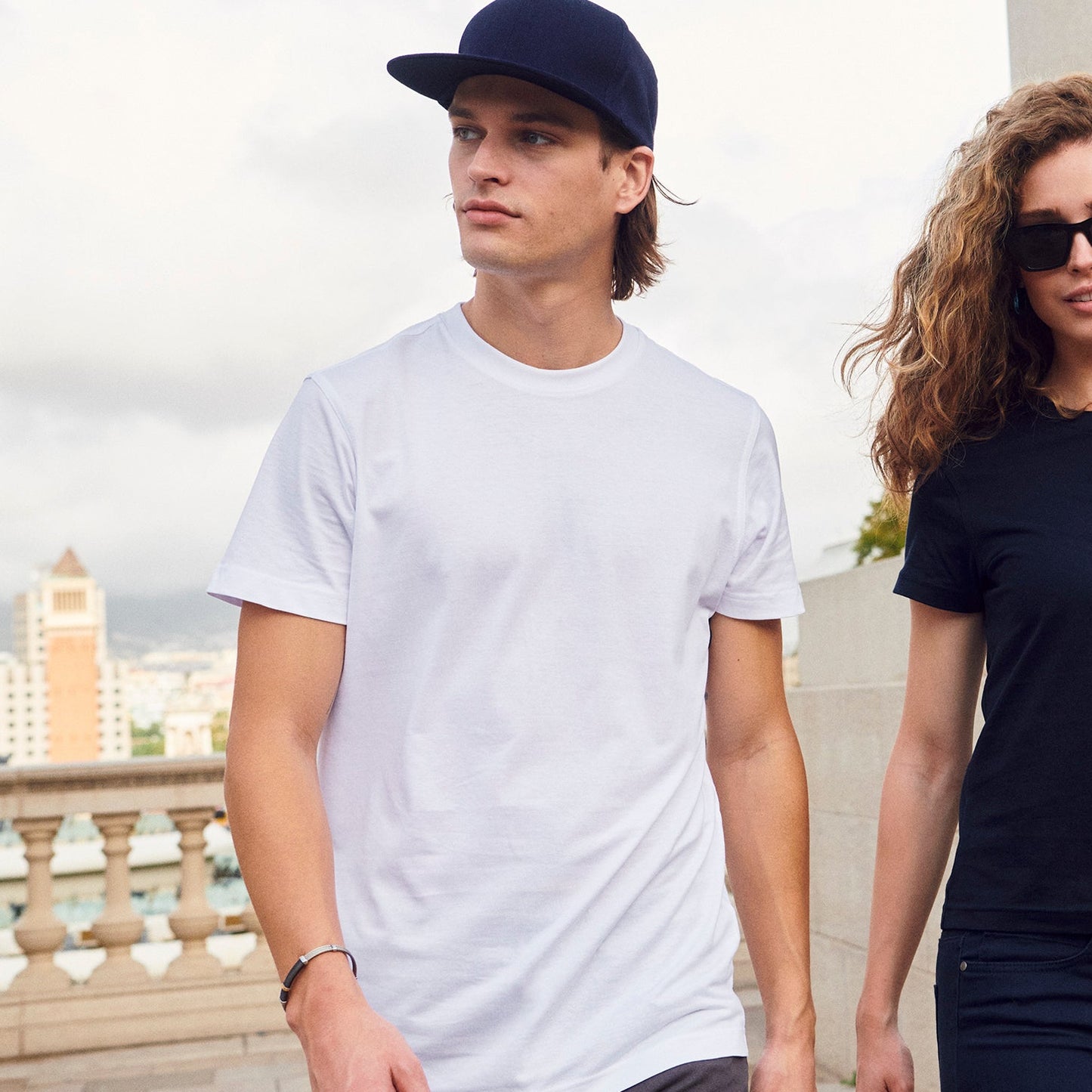 Two people standing outdoors with a cityscape in the background