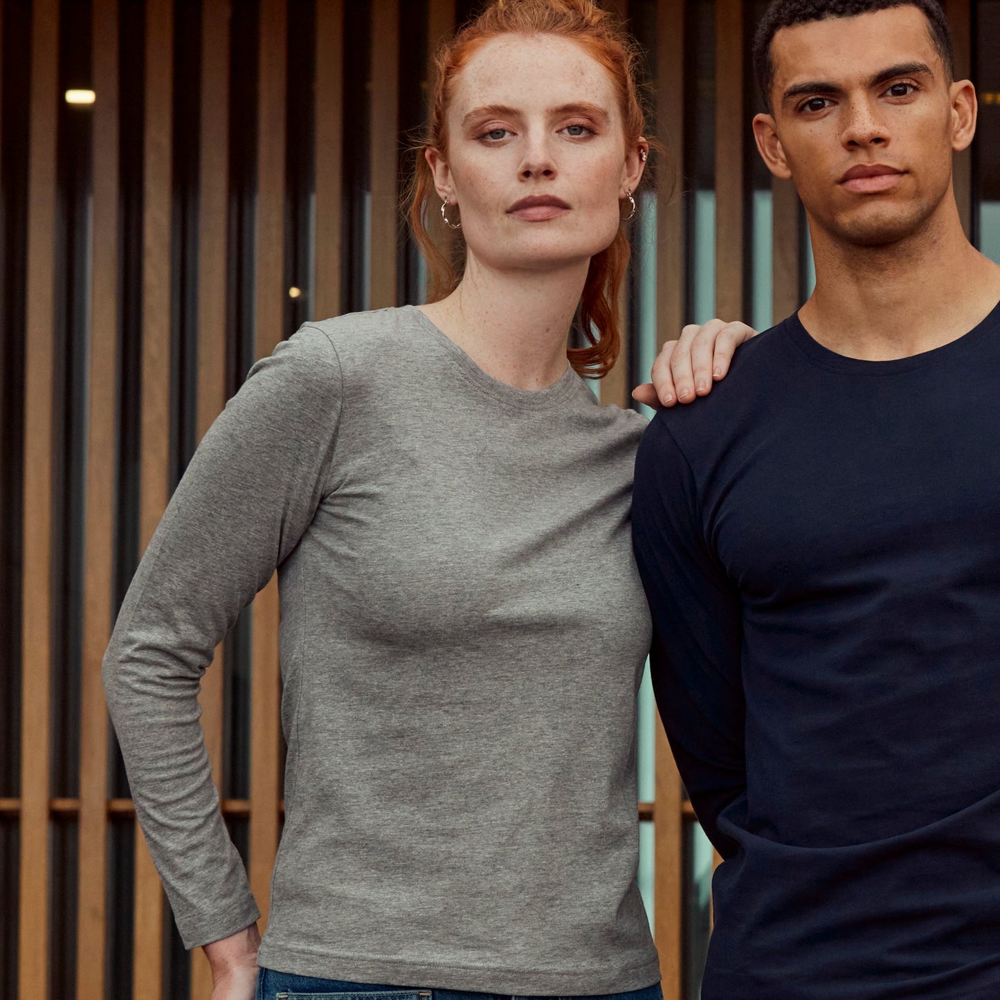 Two people standing together in a modern indoor setting with bookshelves in the background.