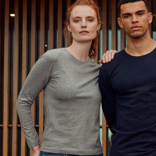 Two people standing together in a modern indoor setting with bookshelves in the background.