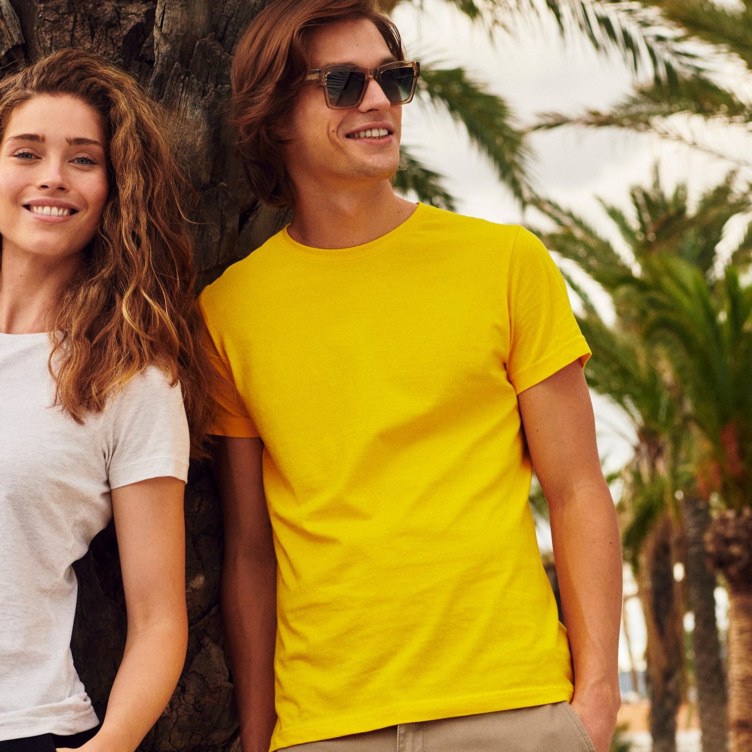 Two people standing next to each other in a park with palm trees in the background.