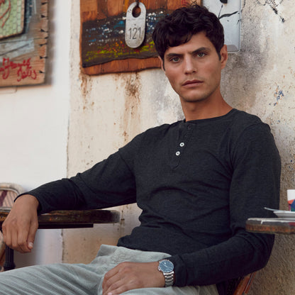 Man sitting in a chair in an artistic setting with paintings on the wall.