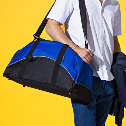 Man holding a blue and black duffel bag against a yellow background