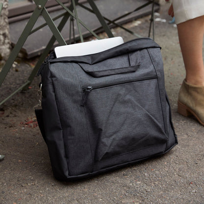 Gray backpack with a white item on top, placed on the ground next to a metal chair.