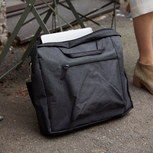 Gray backpack with a white item on top, placed on the ground next to a metal chair.