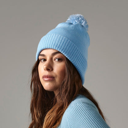 Woman wearing a light blue ribbed sweater and matching beanie against a gray background